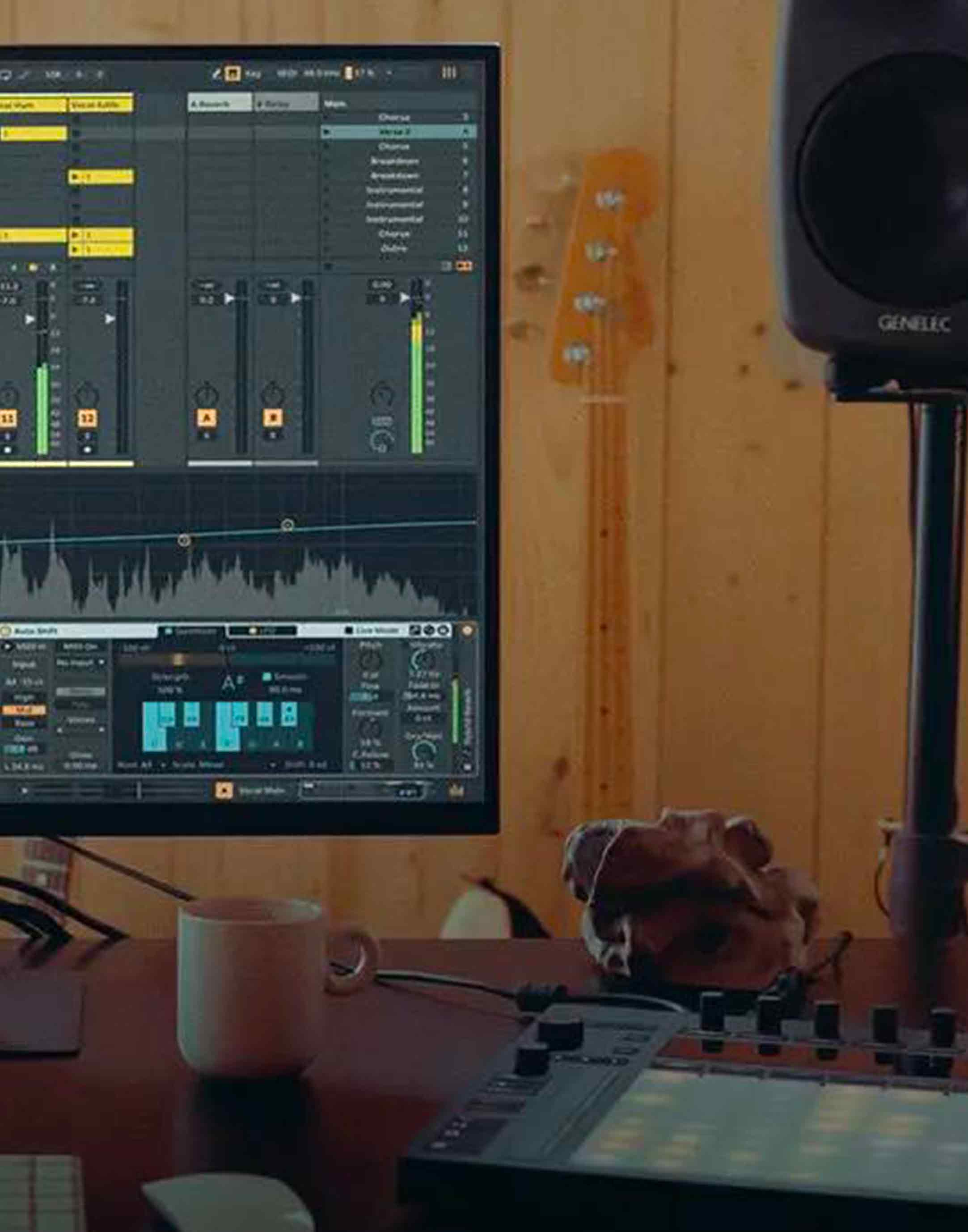 Photo d'un studio audio avec le logiciel Ableton live, un push, une tasse, une enceinte et une guitare en fond